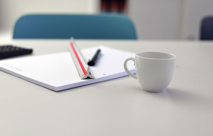 Bild einer Kaffee-Tasse auf einem Schreibtisch mit Block und Lineal